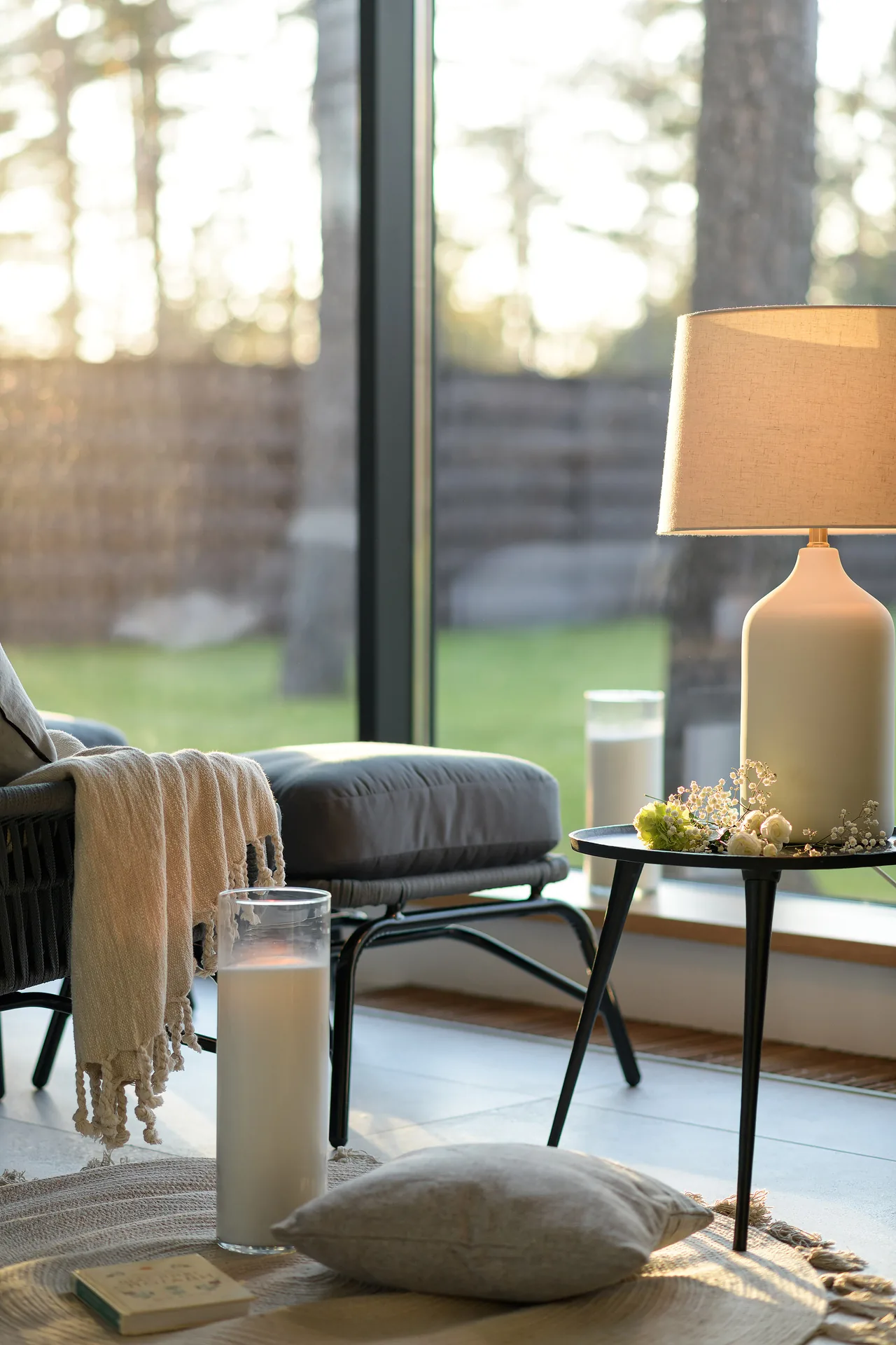 An armchair, candles and a lamp beside a panoramic window