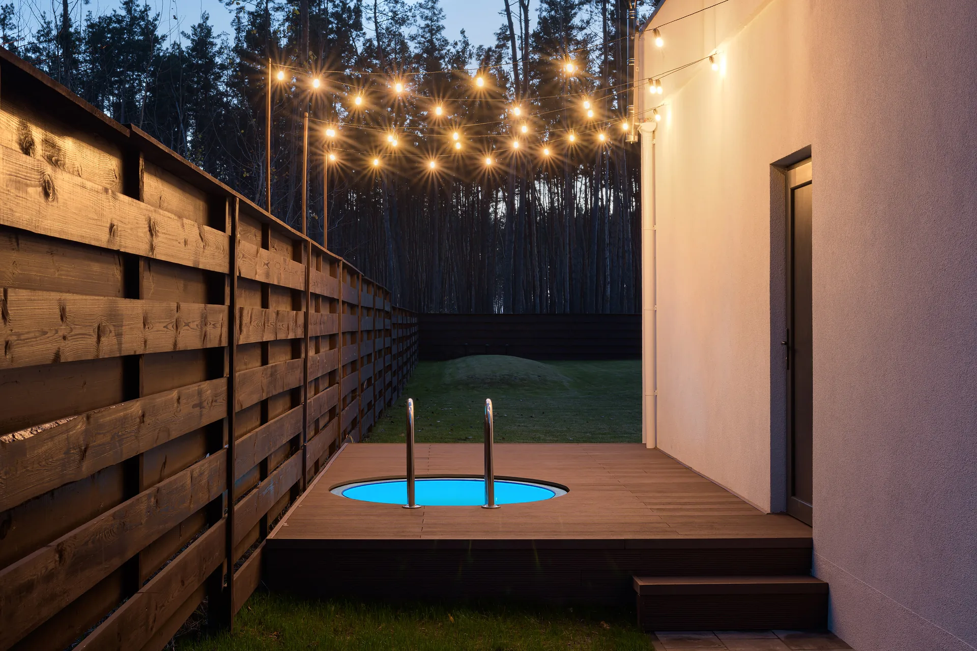 An outdoor plunge pool under evening string lights